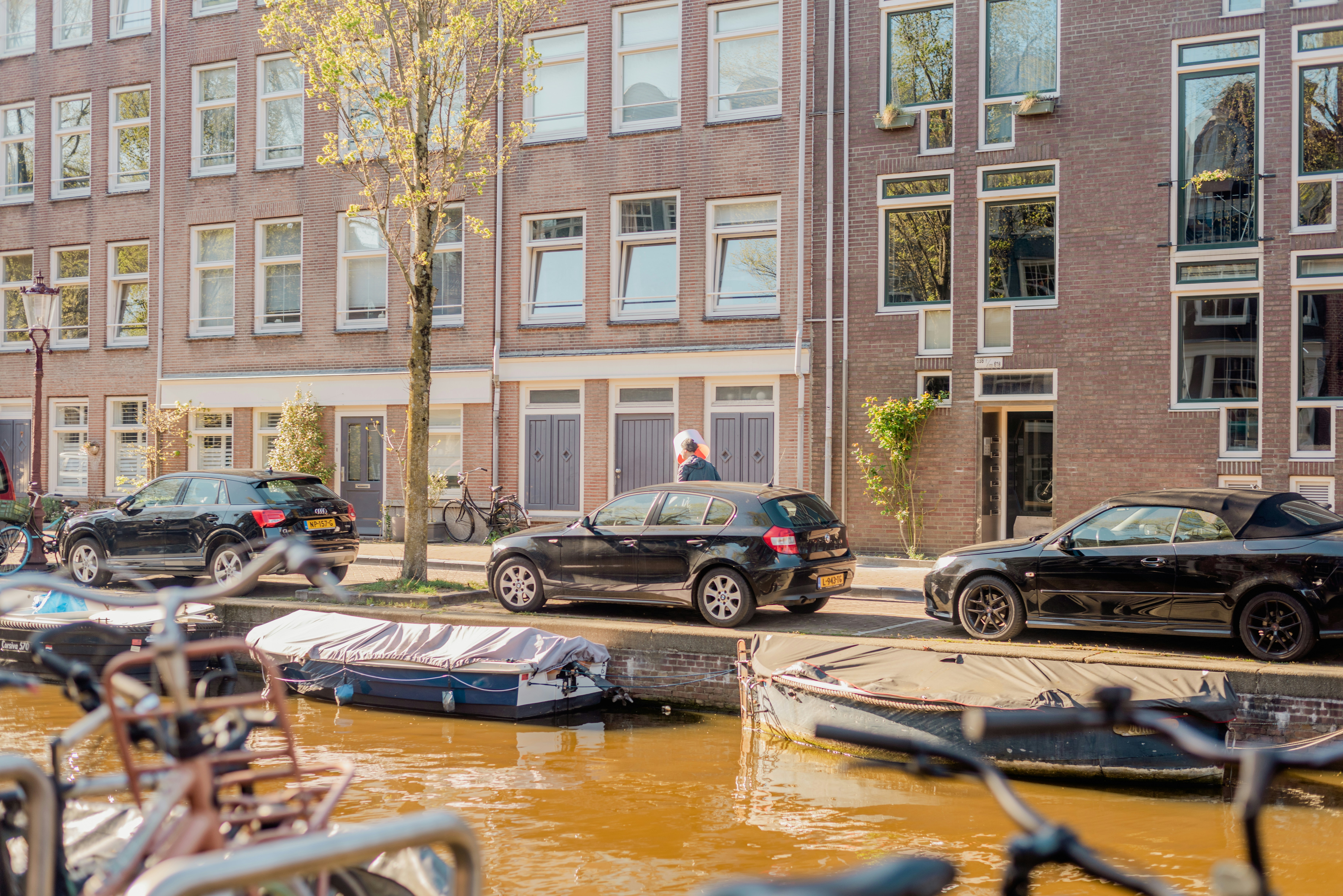 Hollanda'da öğrenci konaklama seçeneklerini temsil eden, kanal kenarındaki geleneksel Hollanda evleri ve önünde park edilmiş bisikletler.