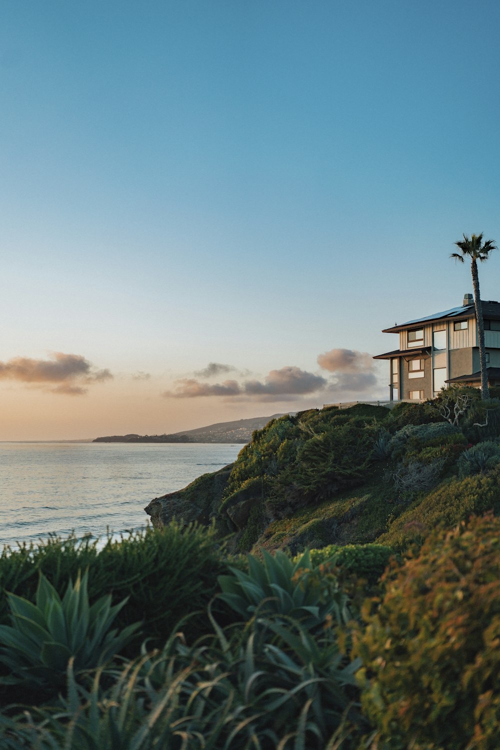 una casa seduta in cima a una collina vicino all'oceano