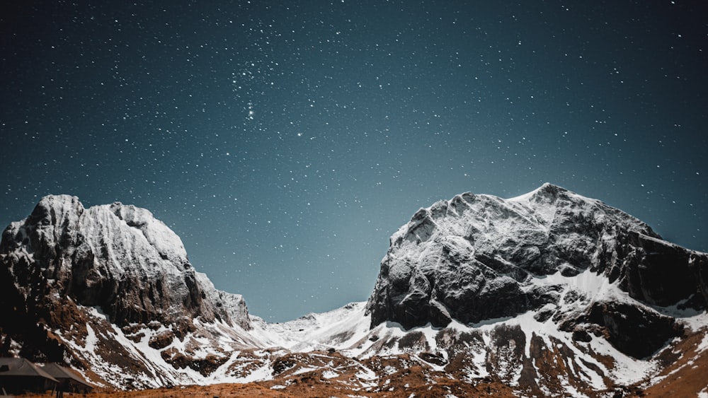 a snow covered mountain range under a night sky