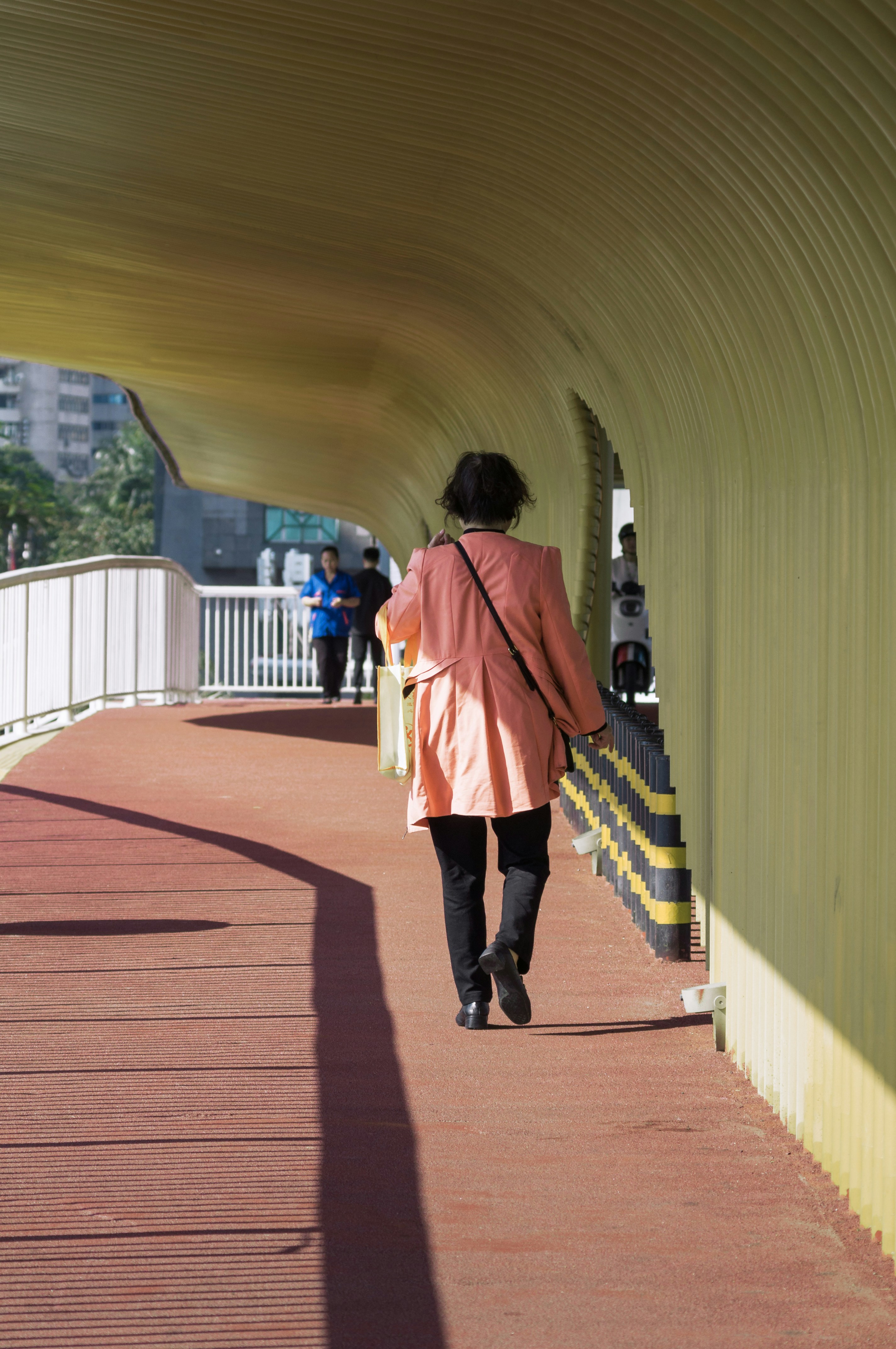 a woman in a pink coat walking down a walkway