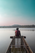 a person sitting on a dock looking out at the water