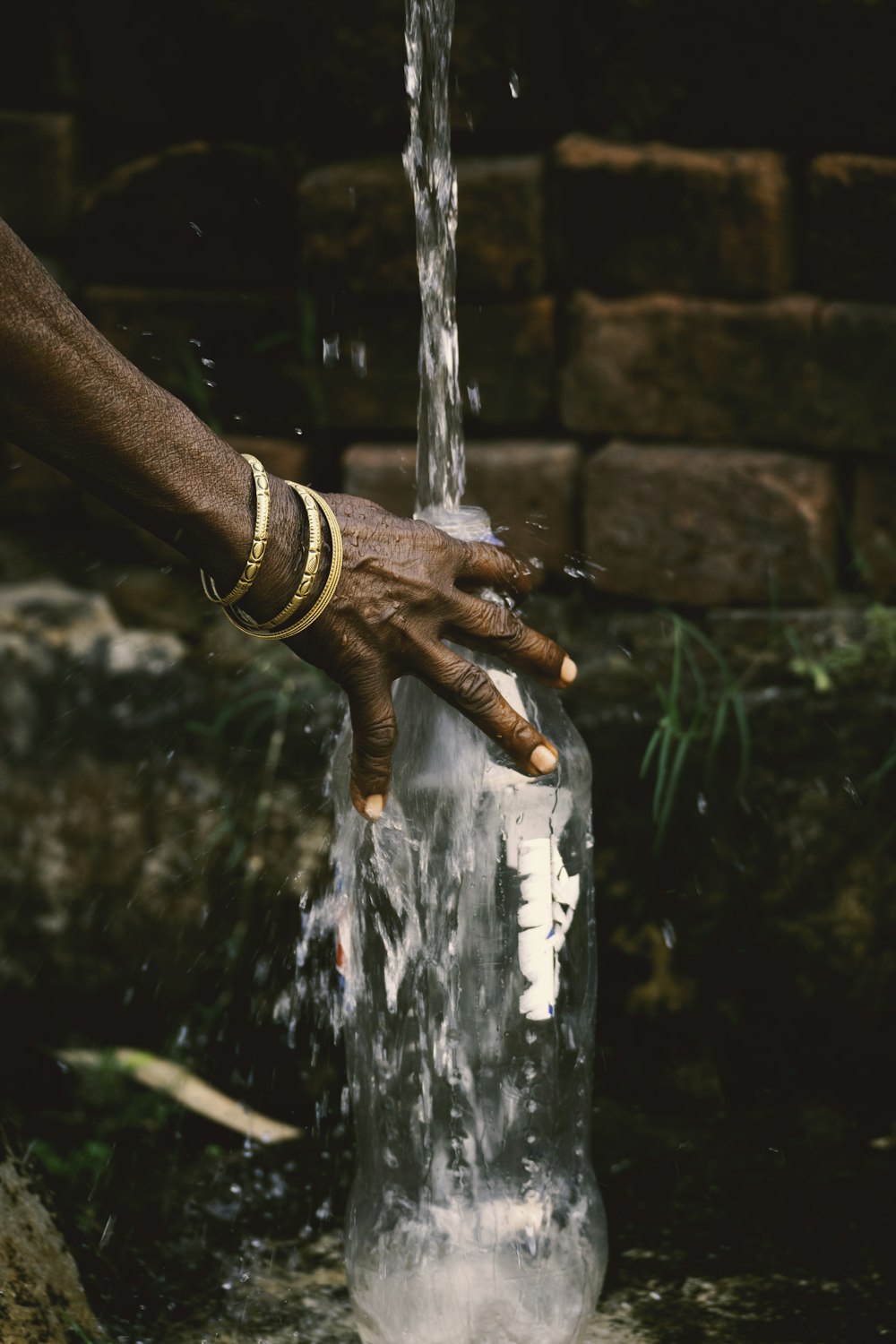 a person's hand is pouring water into a glass bottle