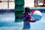 a little girl playing with a beach ball in a pool