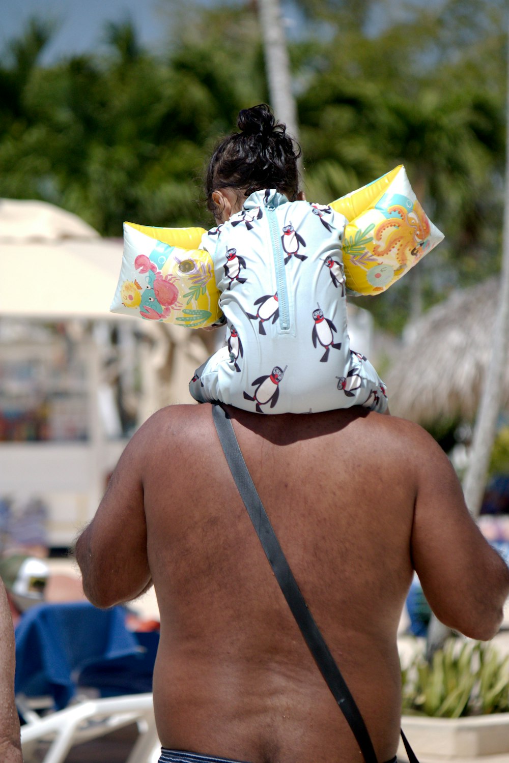 a man in a bathing suit carrying a child on his back
