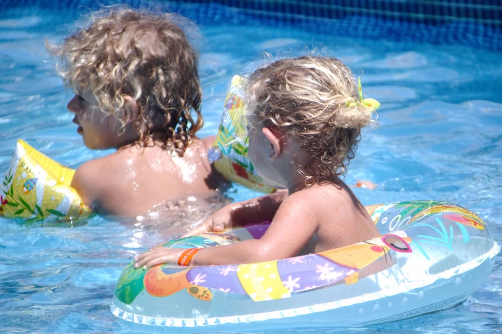 a couple of kids in a pool with a frisbee