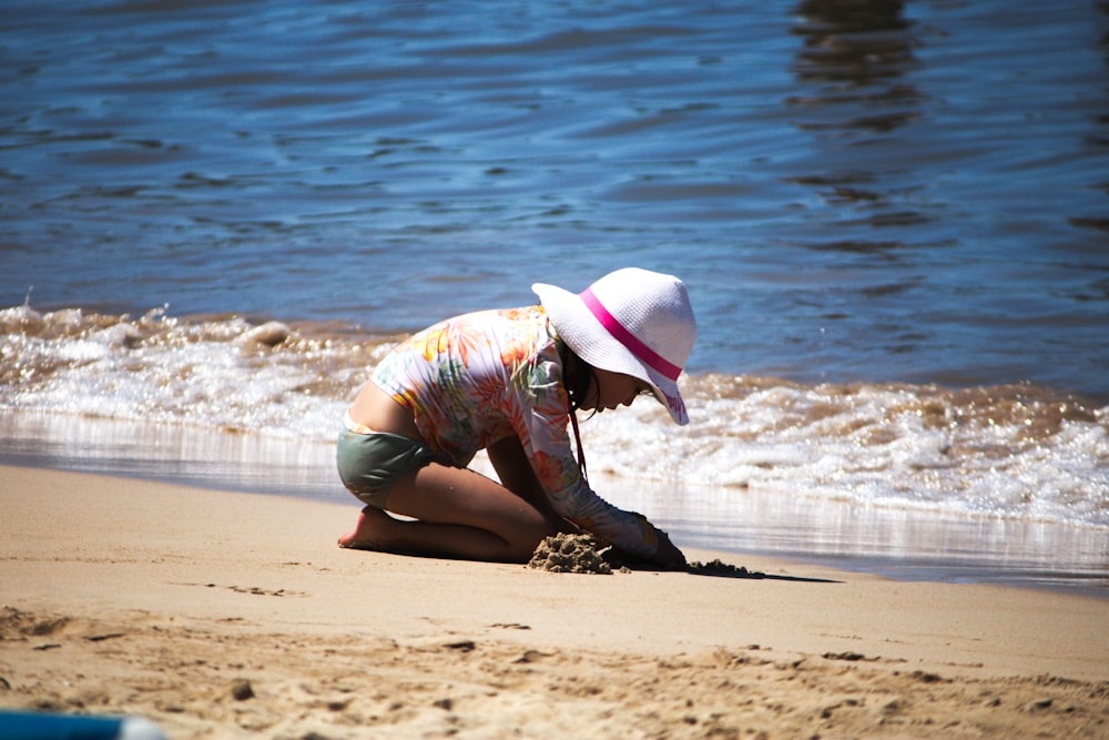 a woman kneeling down on top of a sandy beach