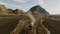 a truck driving down a dirt road in front of a mountain