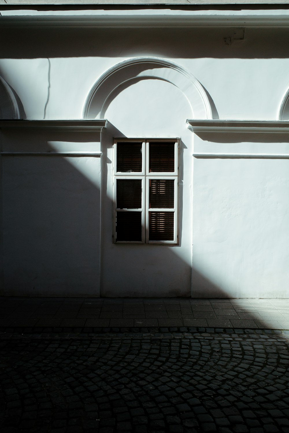 a white building with arched windows and a brick sidewalk