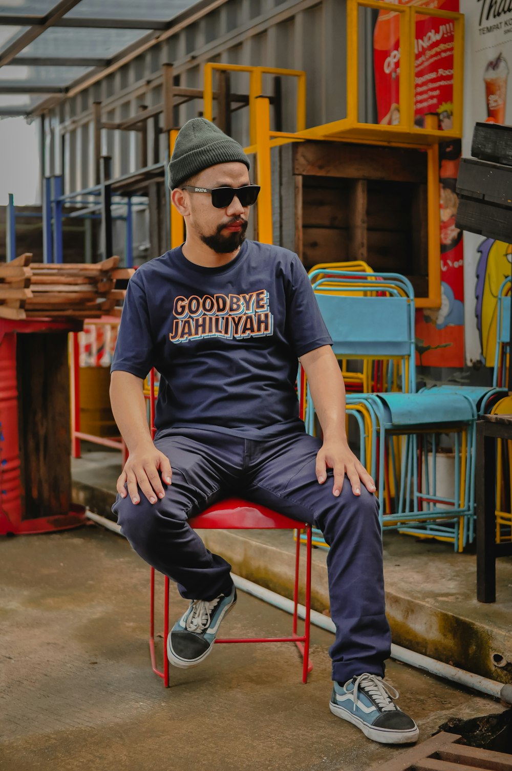 a man sitting on a red chair wearing sunglasses