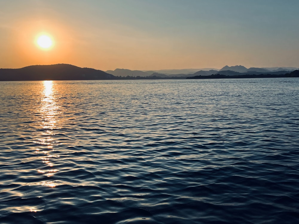 a large body of water with a sunset in the background