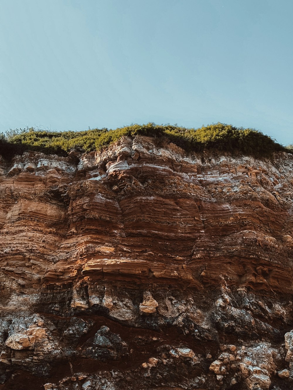 a rocky cliff with a green patch of grass on top of it