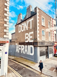 a man walking down a street next to a tall building