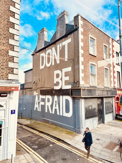 a man walking down a street next to a tall building
