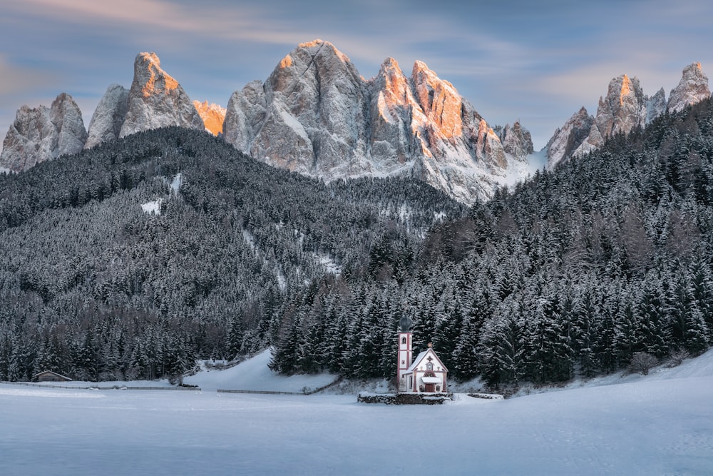 a house in the middle of a lake surrounded by mountains