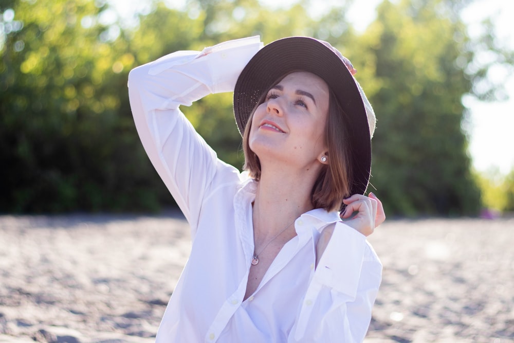 Una donna con un cappello è seduta sulla spiaggia