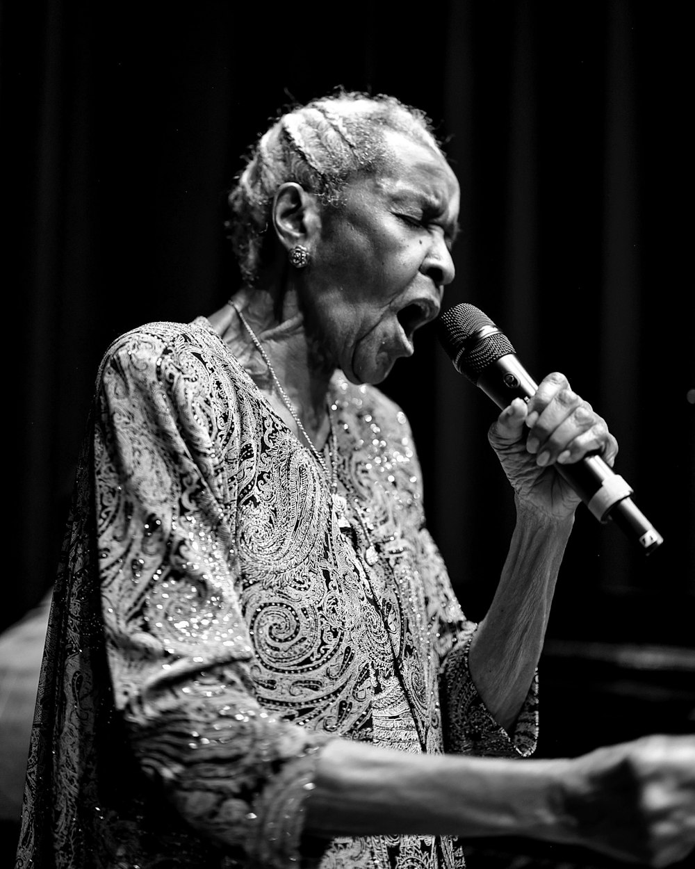 a woman singing into a microphone on stage