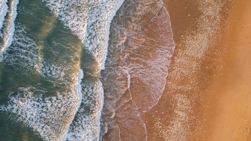 Luftaufnahme eines Strandes mit Wellen und Sand