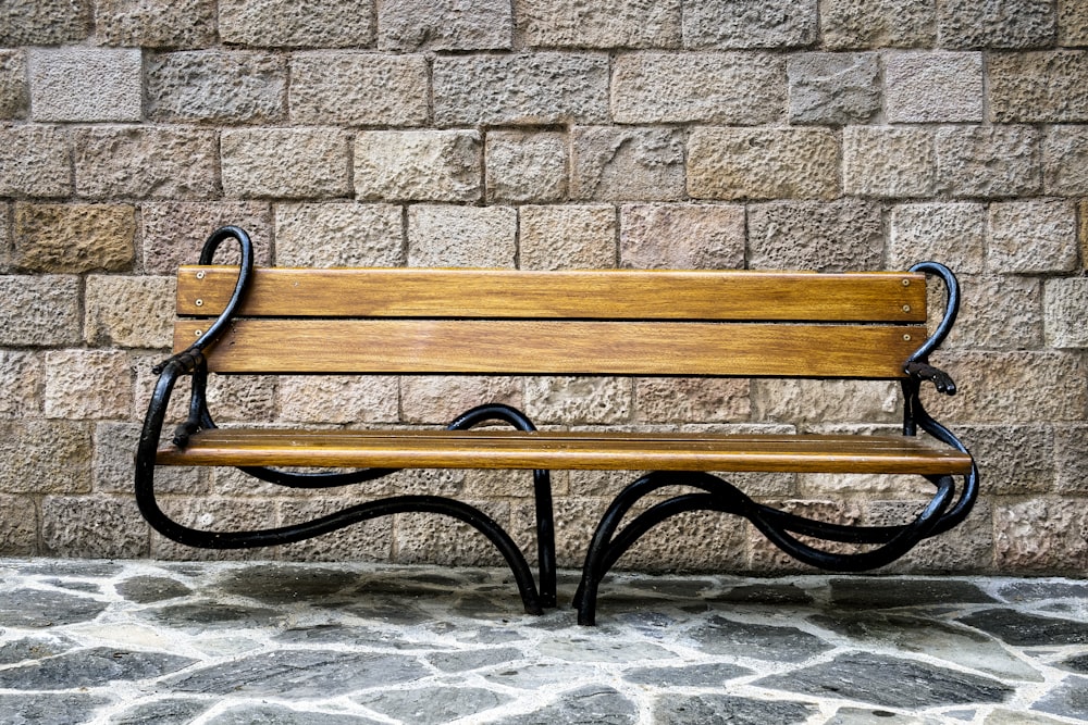 a wooden bench sitting in front of a brick wall