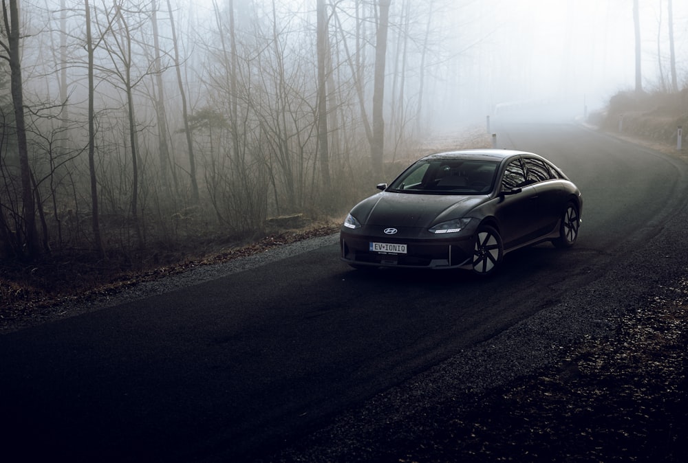 a car driving down a foggy road in the woods