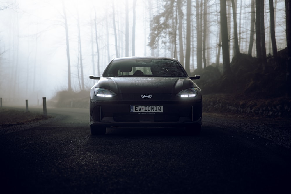 a car driving down a road in the middle of a forest