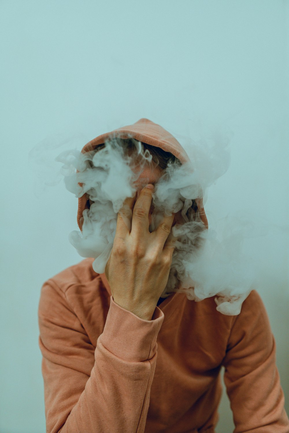 une personne portant un chapeau et soufflant de la fumée ;