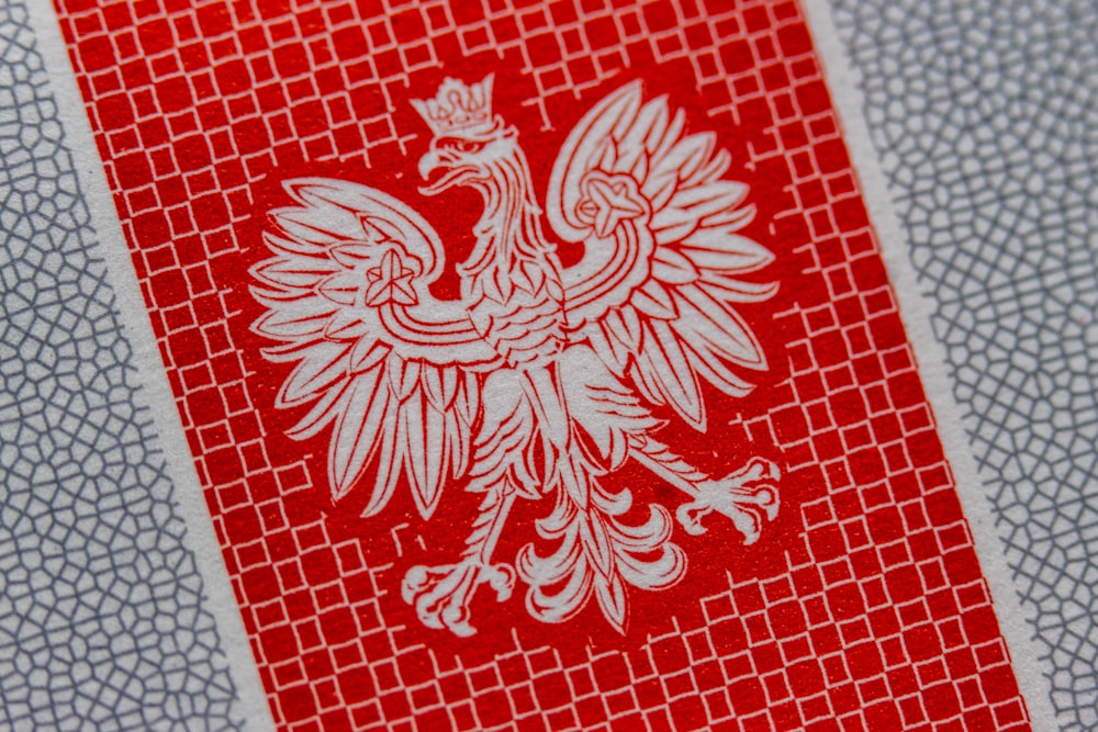 a close up of a red and white paper with a bird on it