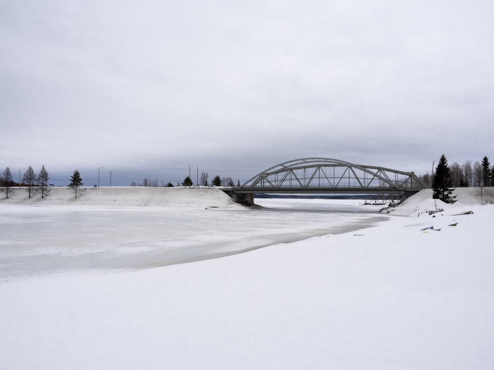 a snow covered field with a bridge in the background