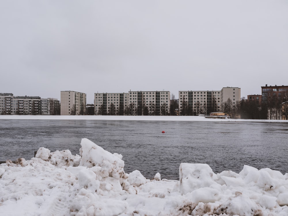 a body of water covered in snow next to tall buildings