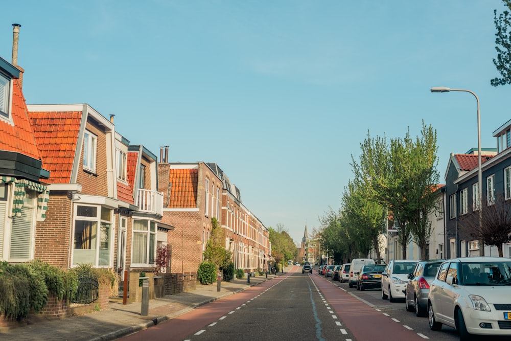 eine Straße, die von geparkten Autos neben hohen Gebäuden gesäumt ist