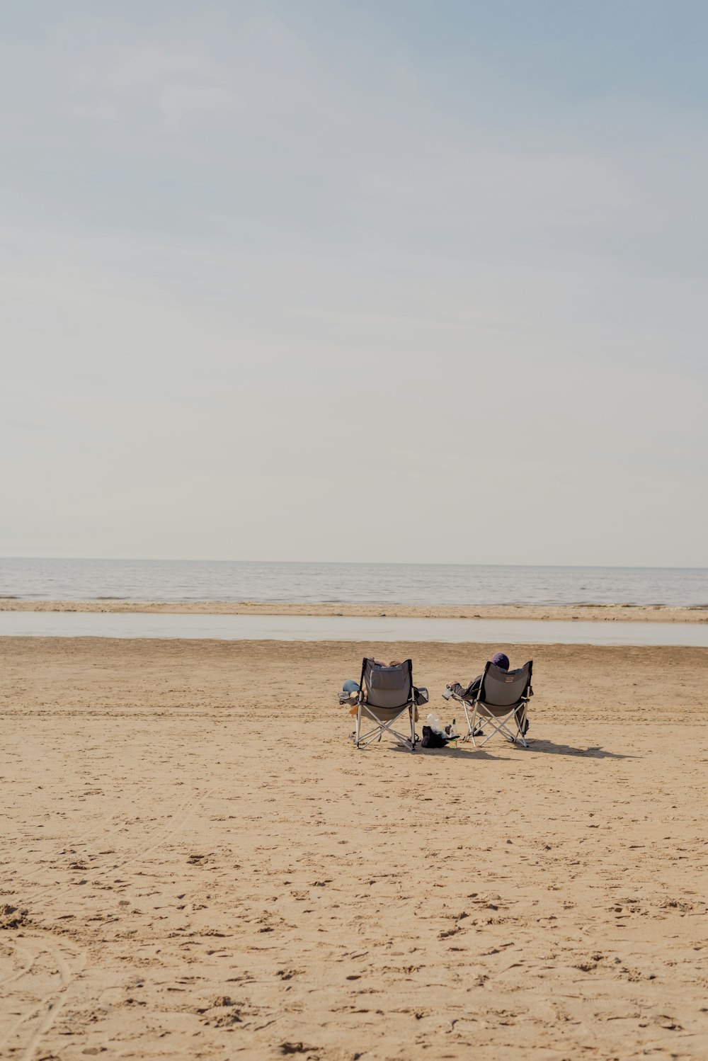 a couple of chairs sitting on top of a sandy beach