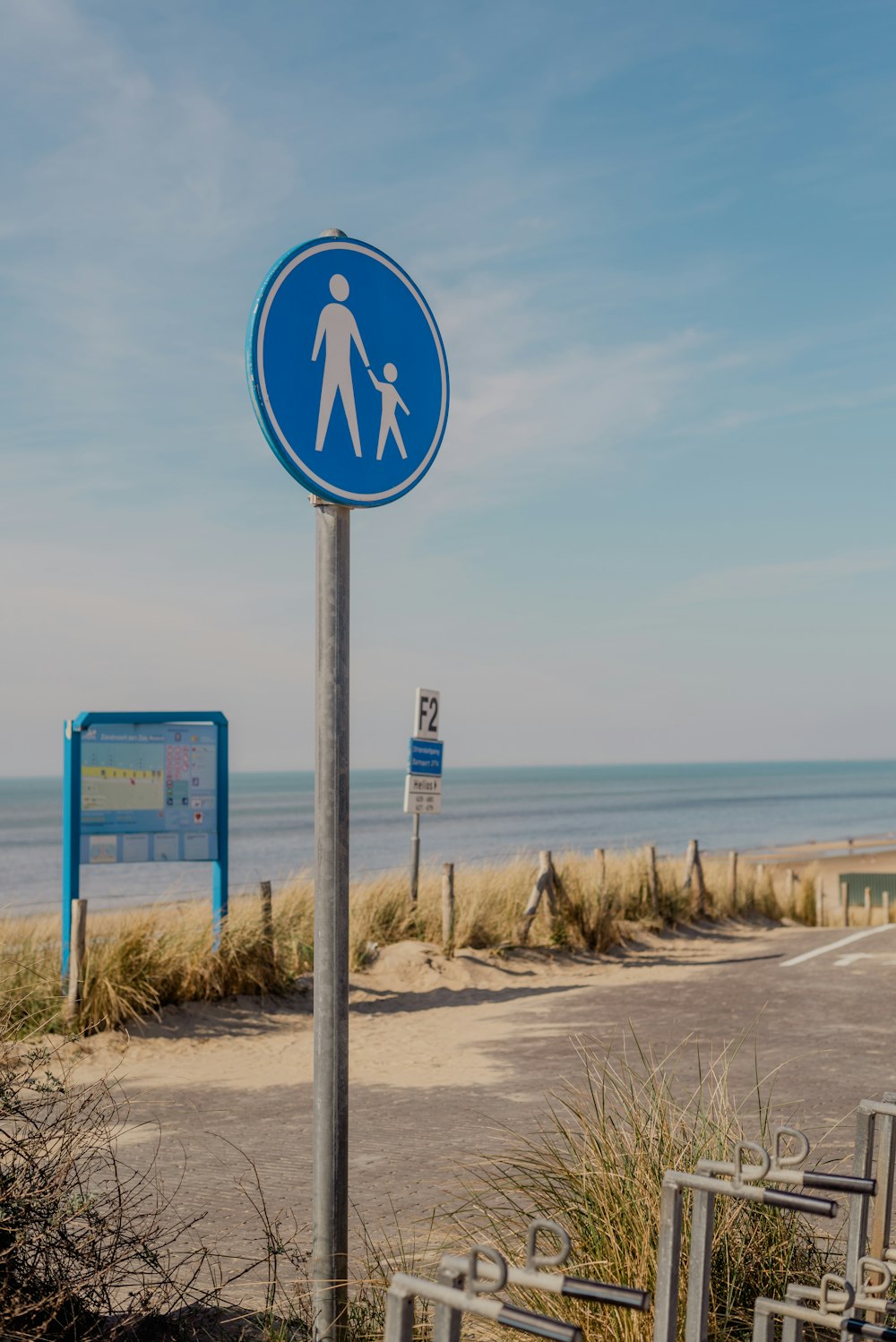 a blue sign on a metal pole next to a beach