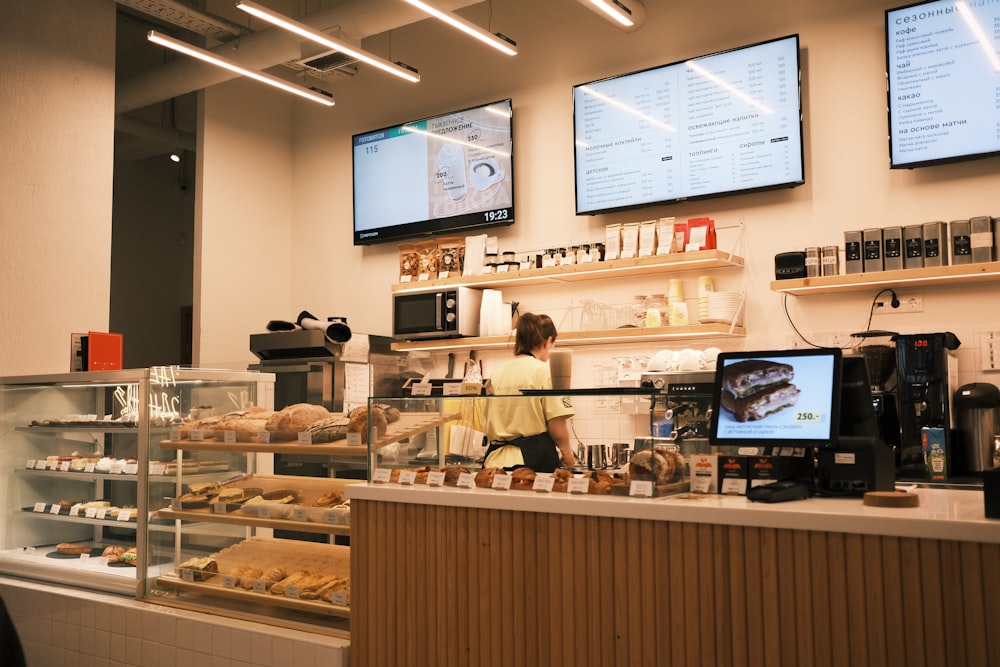 a woman behind the counter of a bakery