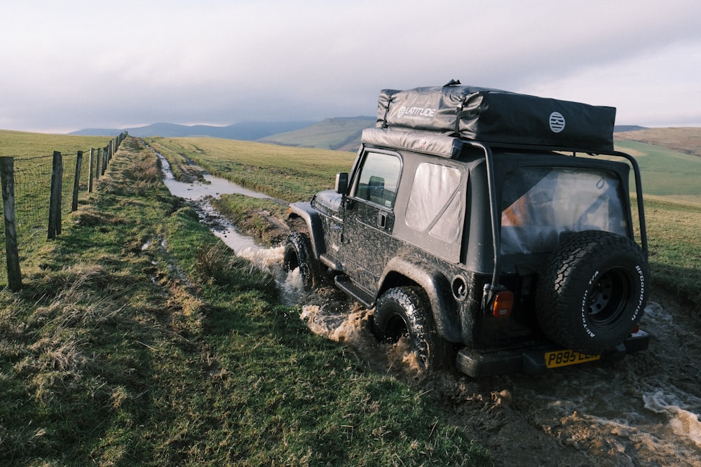 a black jeep driving down a muddy road