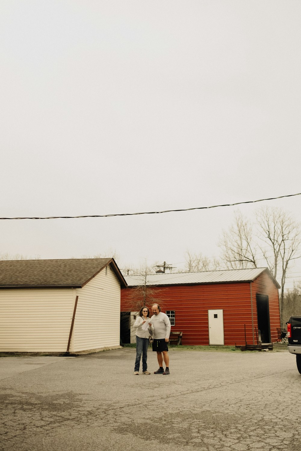 a man and woman standing in front of a red barn