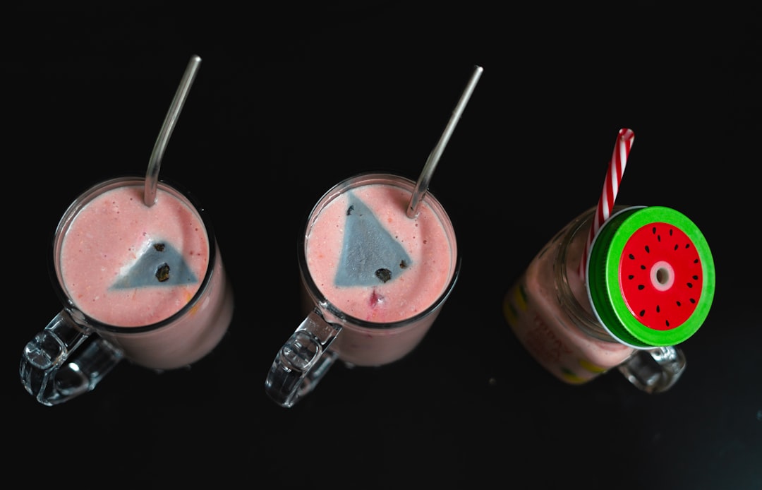 three glasses of smoothie with strawberries and a slice of watermelon