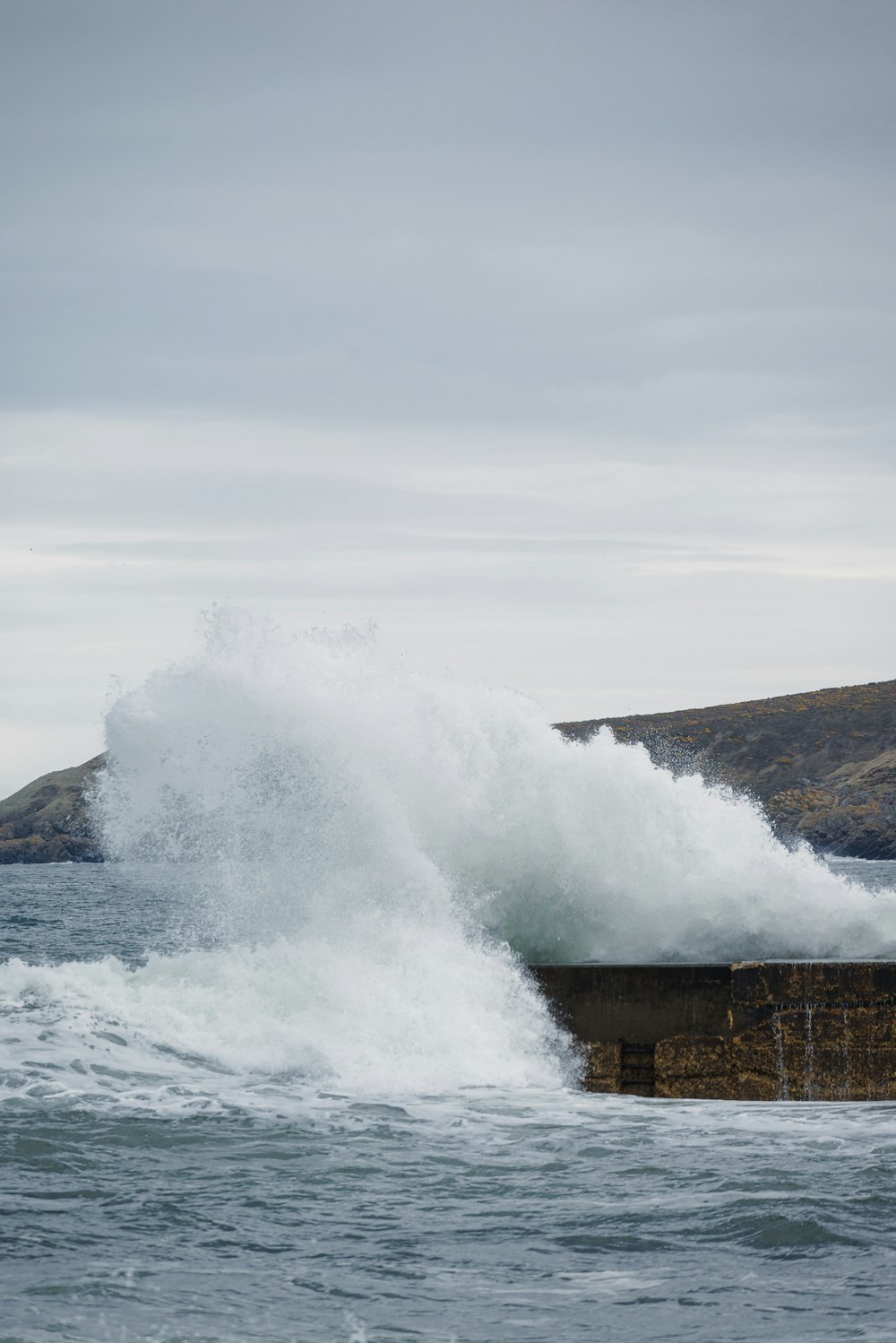 a large wave crashing into the shore of a body of water