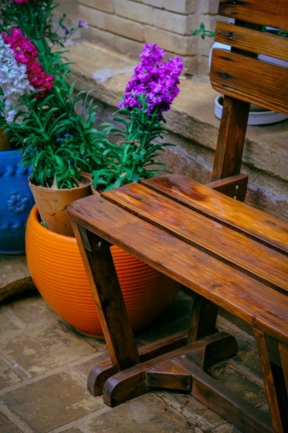 a wooden bench sitting next to a flower pot