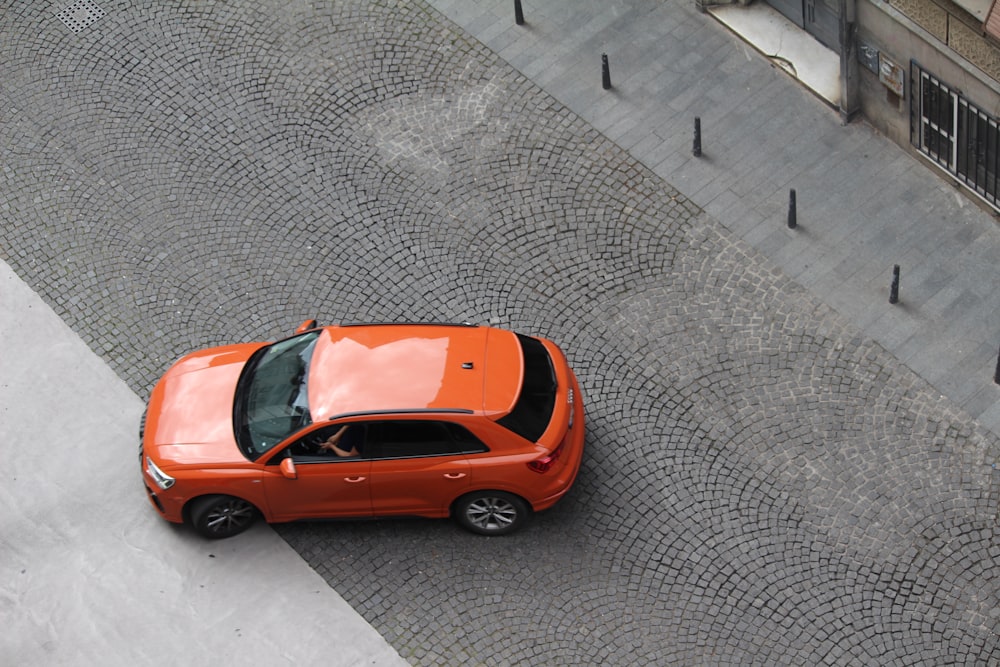 an orange car is parked on a cobblestone street