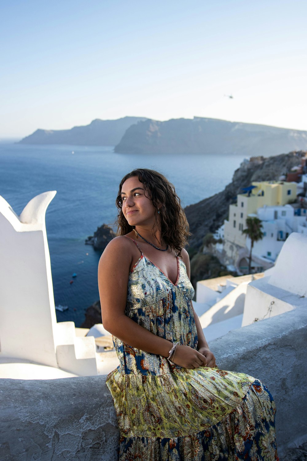 a woman sitting on a ledge overlooking the ocean