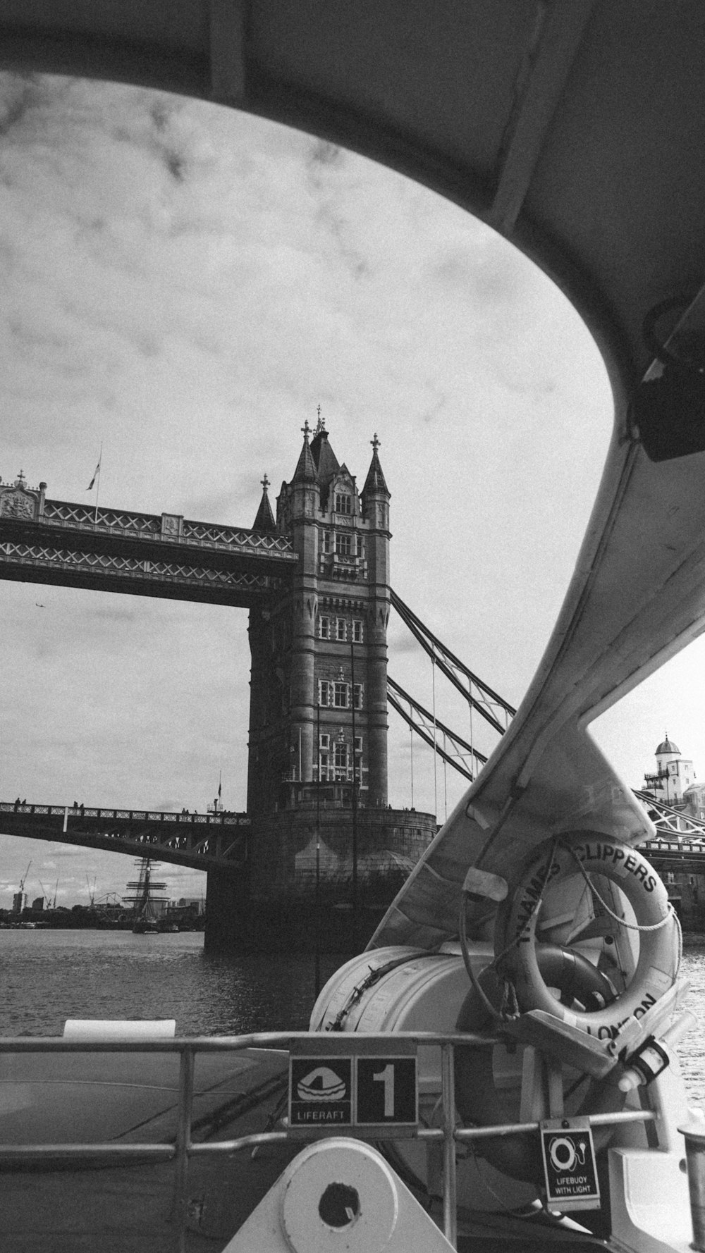 a black and white photo of a boat in front of a bridge