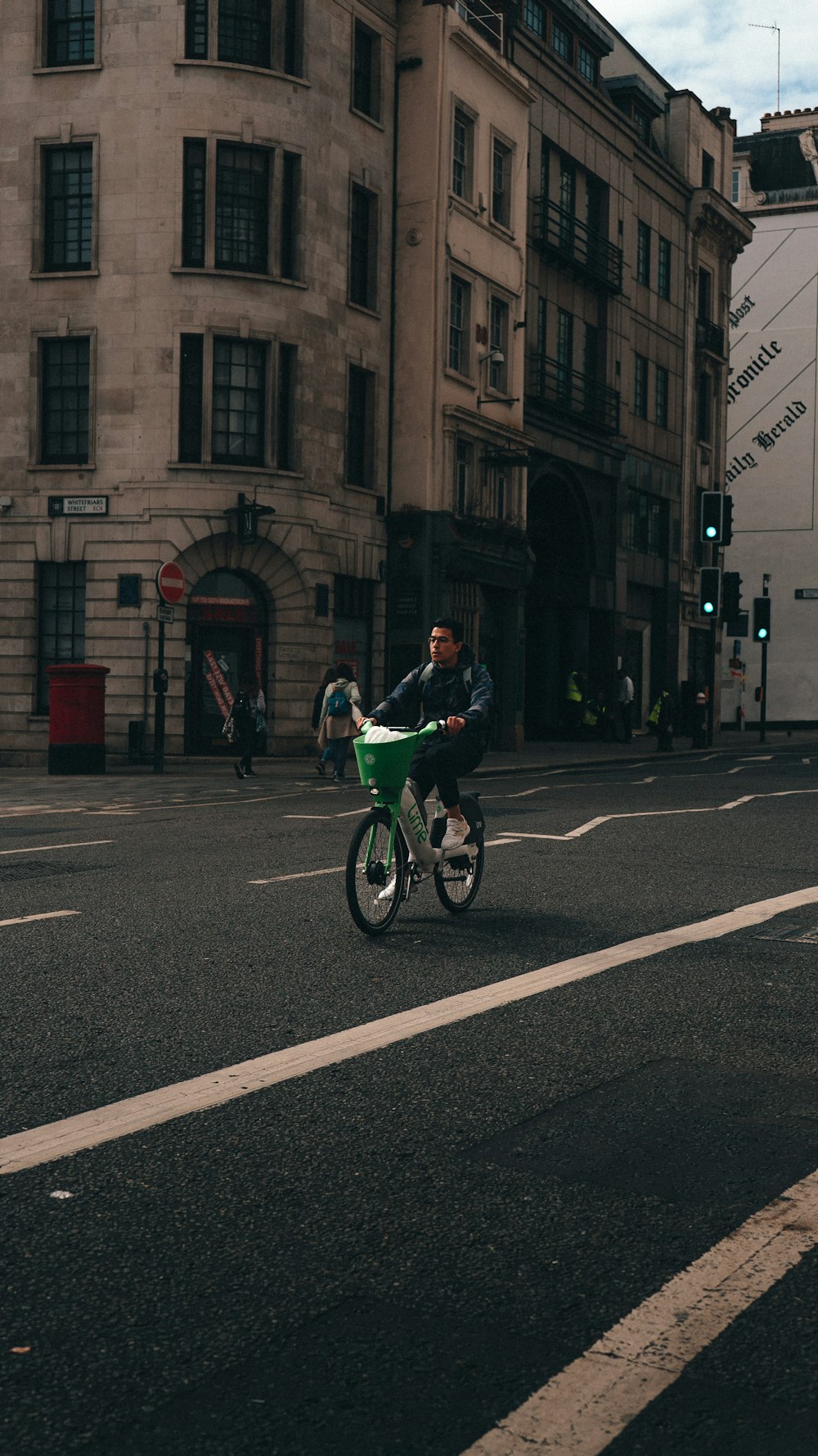 a man riding a small green bike down a street