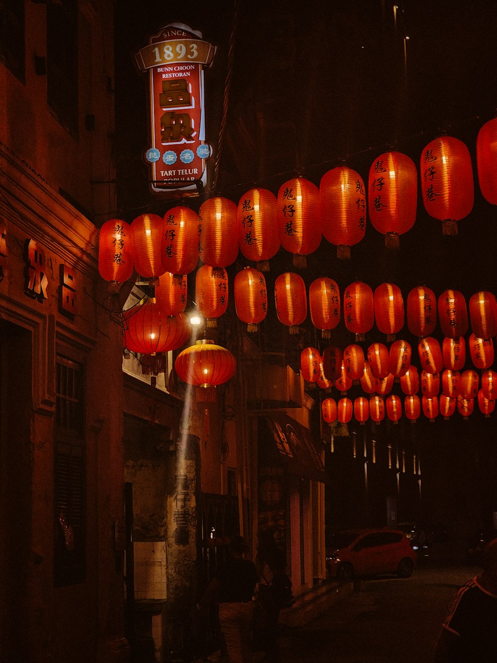 a group of red lanterns hanging from the side of a building
