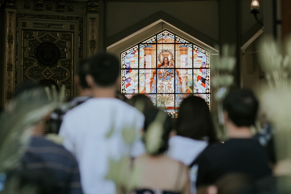 a group of people standing in front of a stained glass window