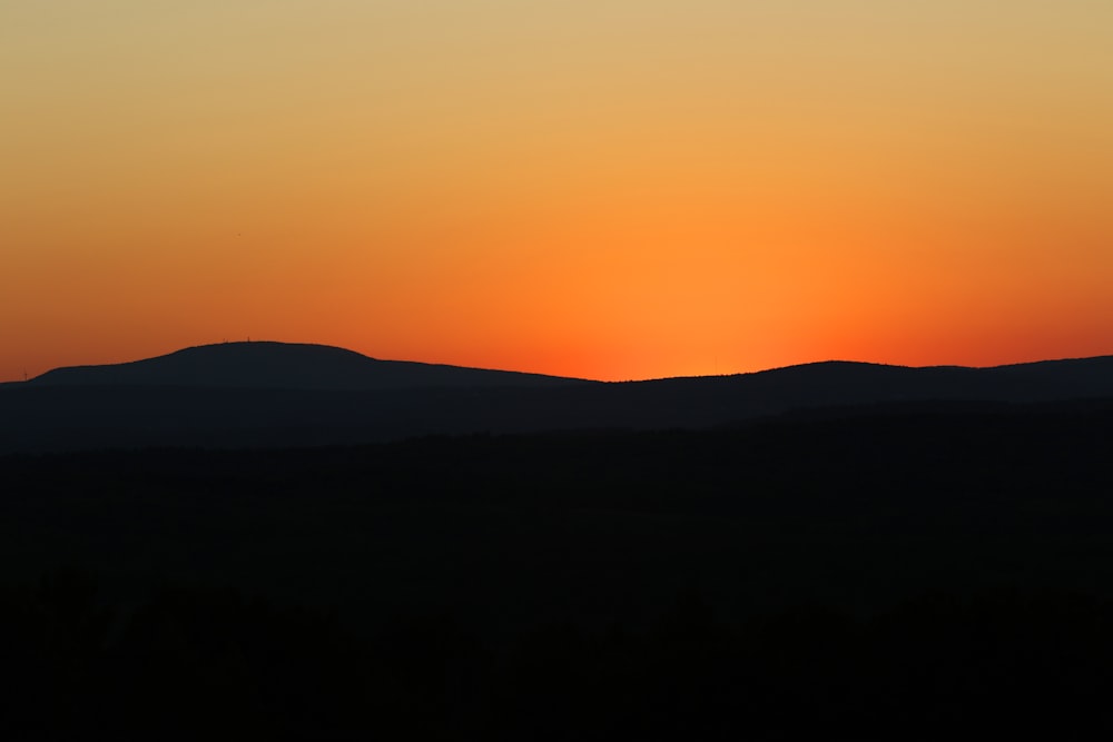 the sun is setting over a mountain range