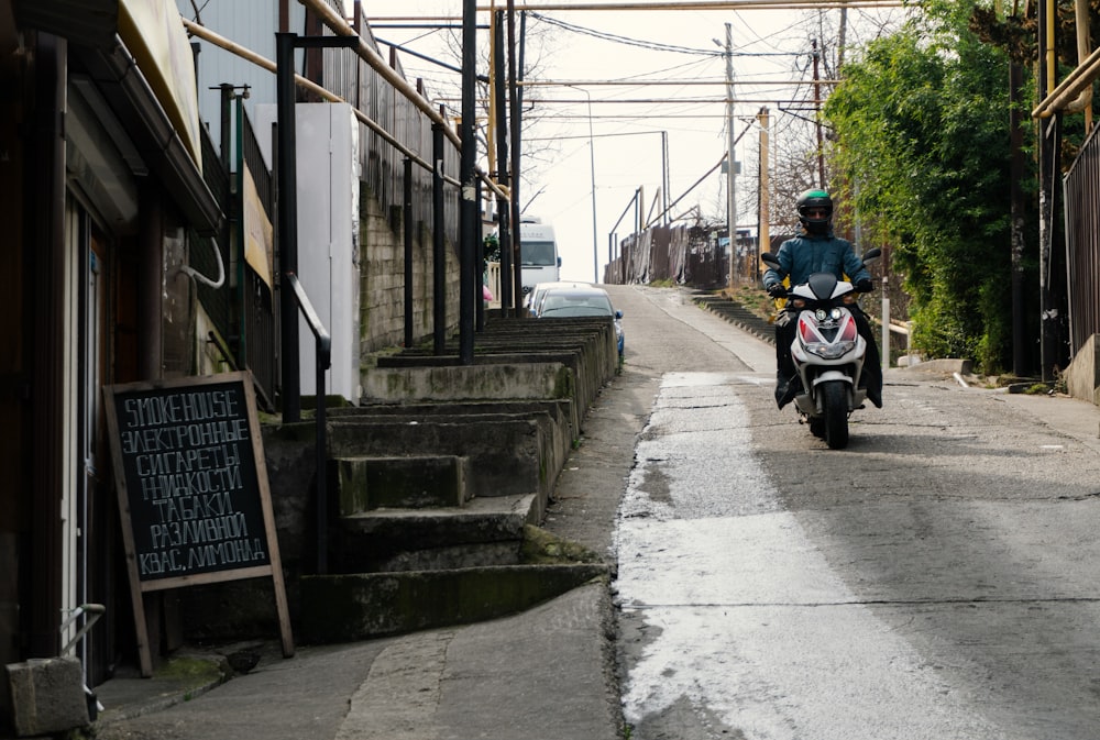 a man riding a motorcycle down a narrow street