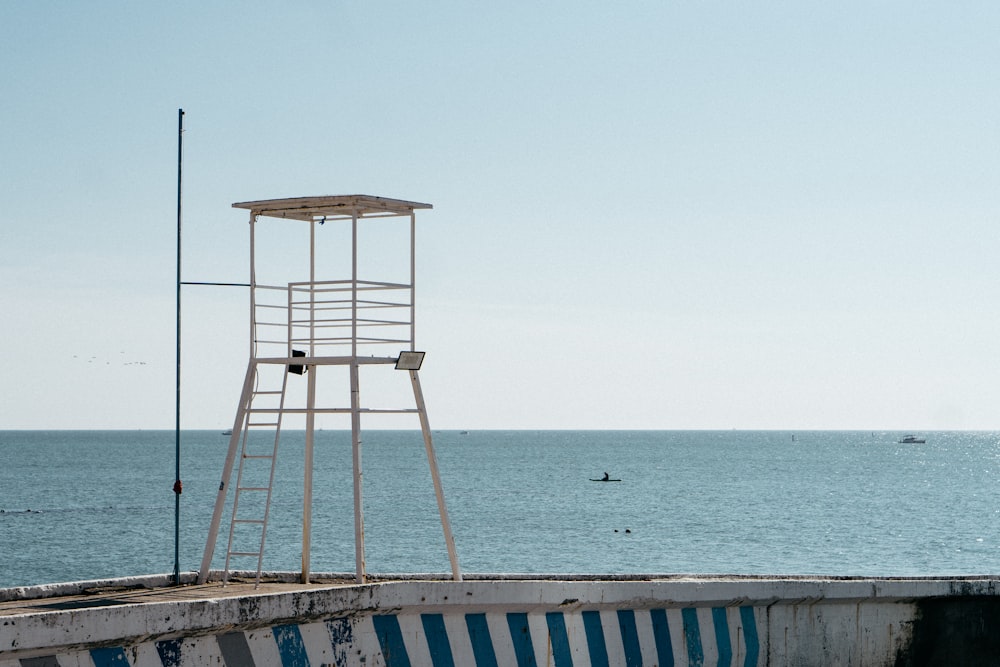 a lifeguard tower sitting on top of a cement wall next to the ocean