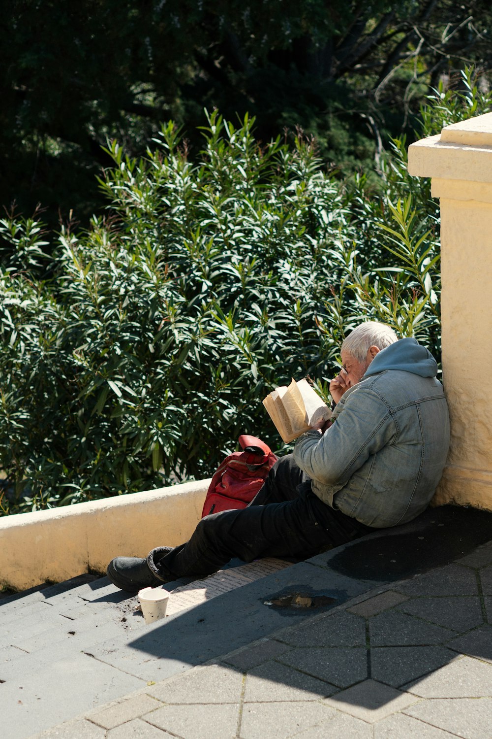 a man sitting on a ledge reading a book