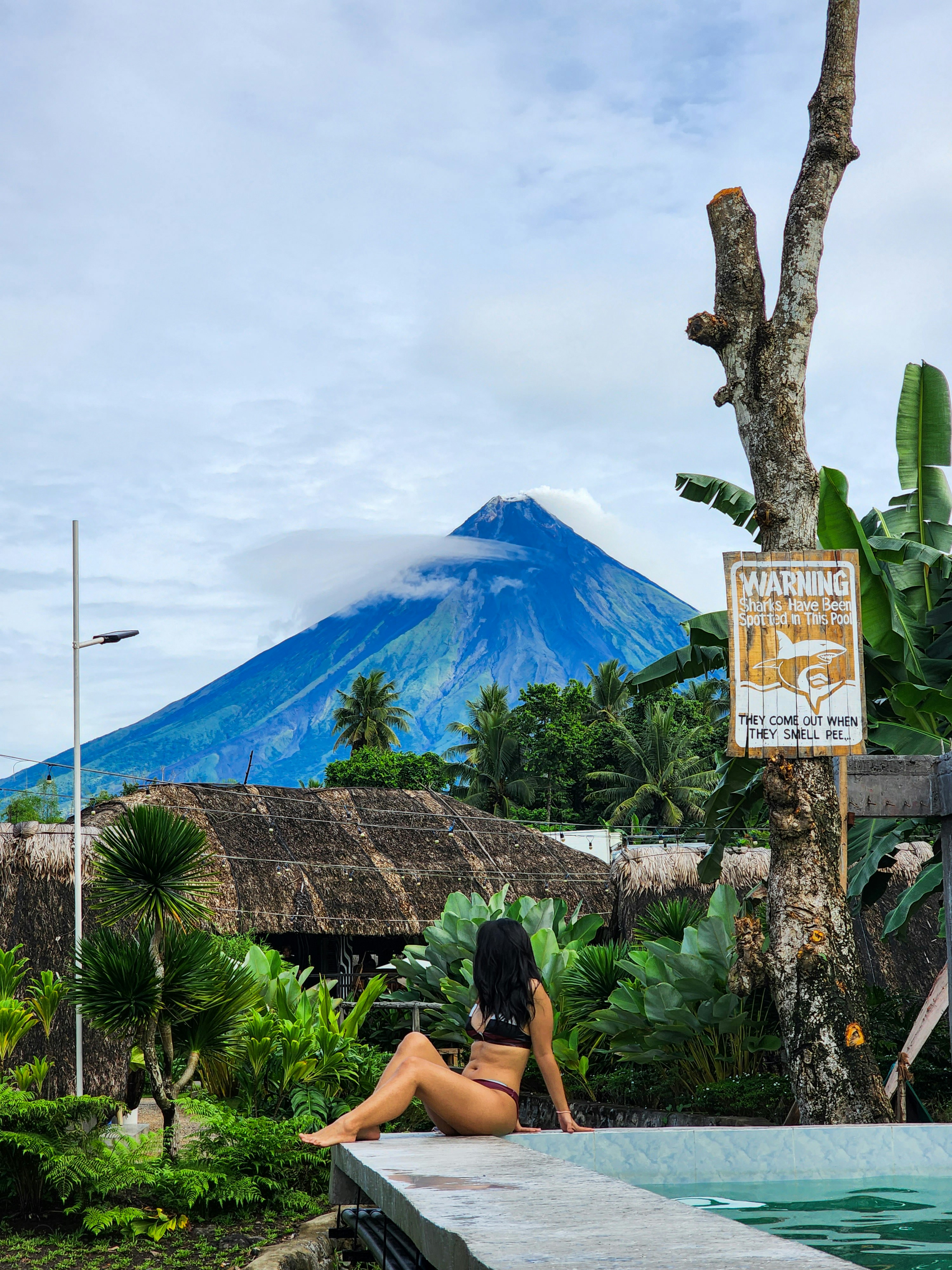 a woman in a bikini sitting next to a pool
