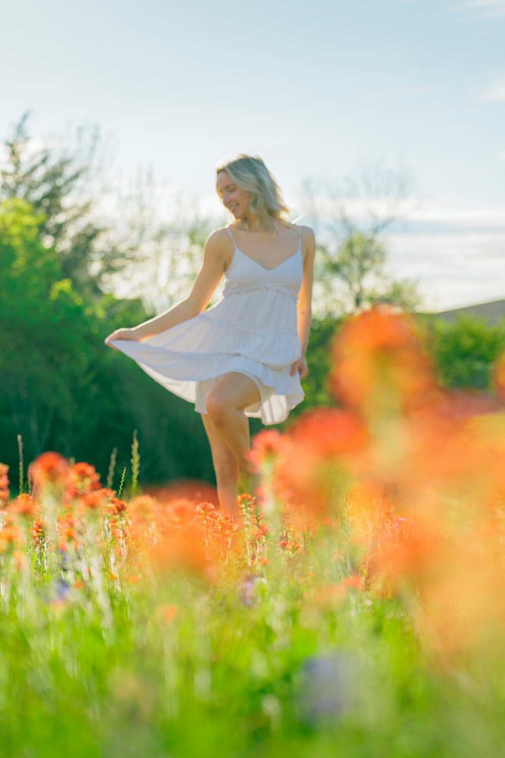 a woman in a white dress standing in a field of flowers