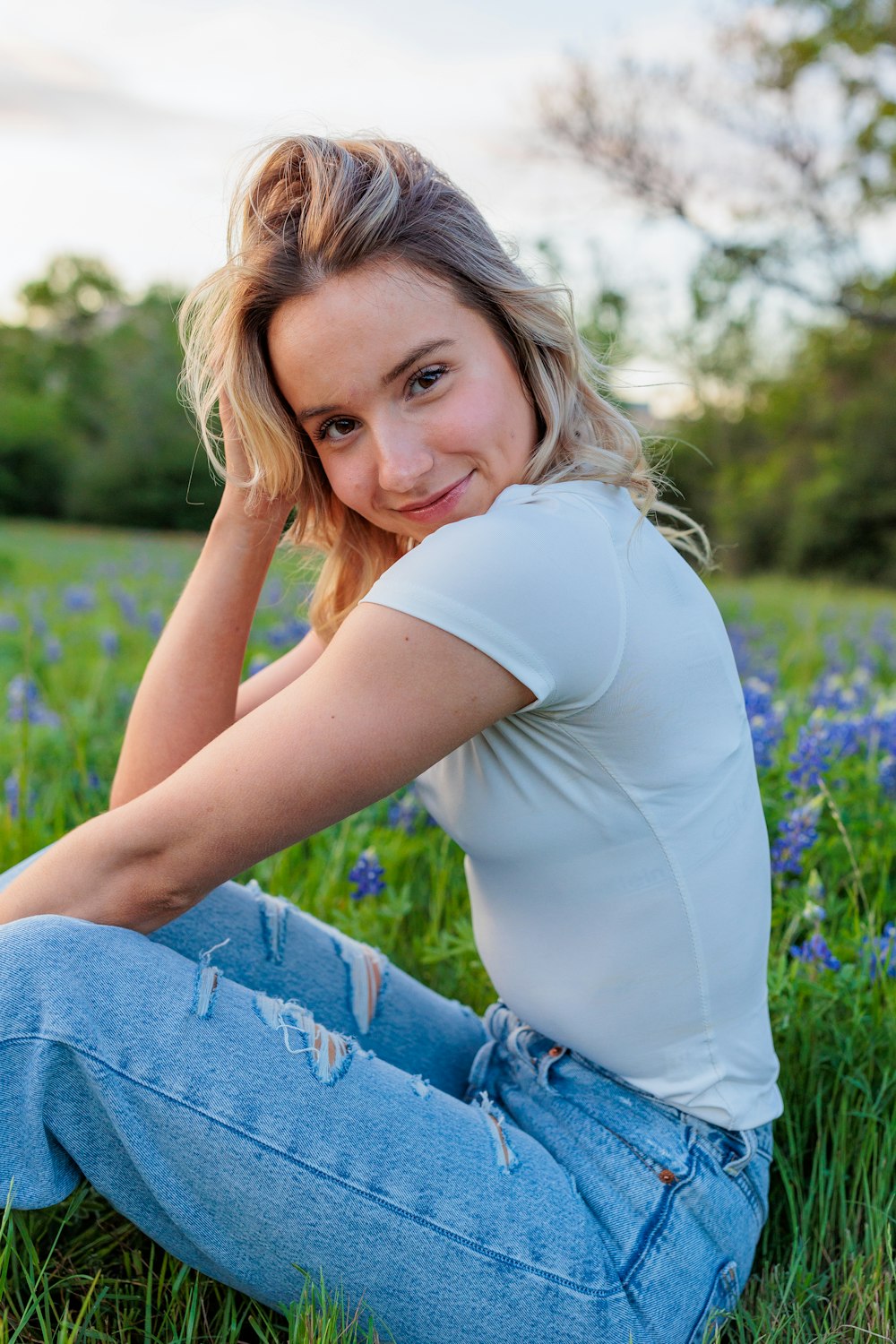 a woman sitting in a field of blue flowers